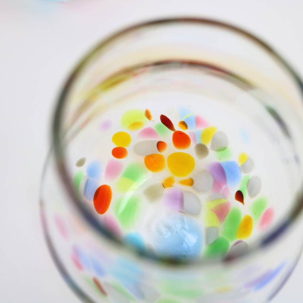 Top down view of a stemless wine glass with colourful bottoms