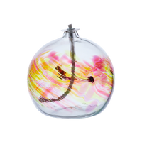 Flat-bottomed glass orb with a wick with orange, pink and yellow coloured glass around the middle and horizontal webbing on a transparent background.